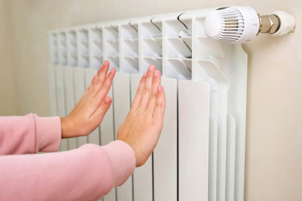 l'enfant se tient les mains près du radiateur